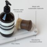 Sandstone Dorai Home Stone Sink Caddy with a dish soap bottle and brush, showing its quick-dry surface.