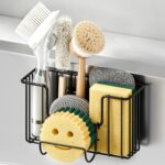 Fikoksol black metal sponge holder hanging inside a kitchen sink, holding a sponge and brush, with the smiley rack attached.