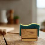 HTB Teak Wood Sponge Holder for kitchen sink, shown on a countertop with a sponge inside, natural wood finish.