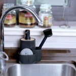 A matte black Kmass Kmaxx 3-in-1 sink caddy organizer with a soap dispenser, sponge, and dish brush holder.