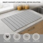Light gray Nestive foldable diatomite stone drying mat with dishes and cups drying on a kitchen counter