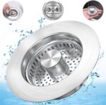 Close-up of a silver brushed stainless steel kitchen sink drain strainer with pop-up stopper in a kitchen sink.