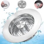 Close-up of a silver brushed stainless steel kitchen sink drain strainer with pop-up stopper in a kitchen sink.