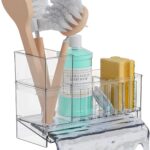 A clear plastic SuoXing sink caddy with multiple compartments holding sponges, a dish brush, and soap bottles.