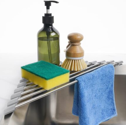 Gray Tomorotec triangle roll-up dish drying rack extended over a sink corner with dishes and sponges on it.